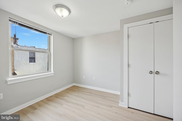 unfurnished bedroom featuring light wood-type flooring and a closet