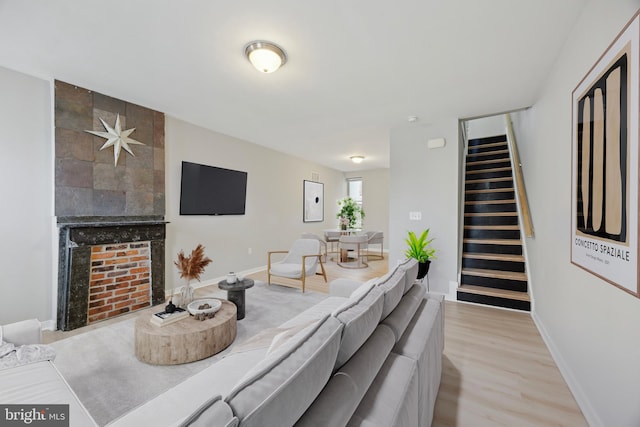 living room featuring a tile fireplace and light wood-type flooring