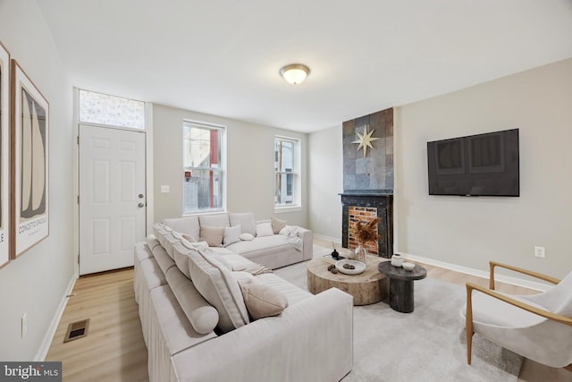 living room with a tile fireplace and light wood-type flooring