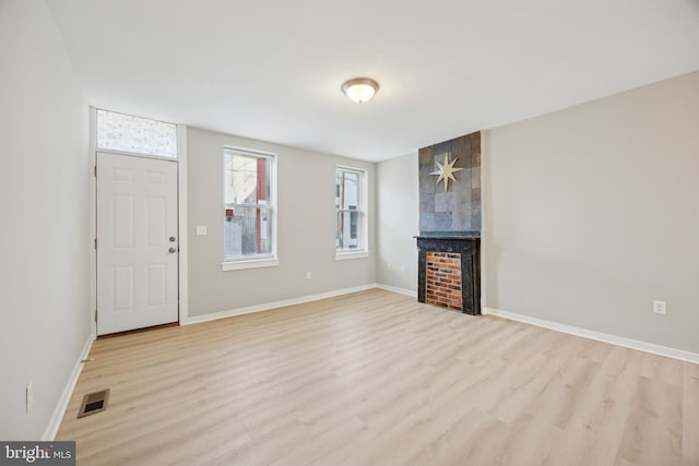 unfurnished living room with a large fireplace and light wood-type flooring