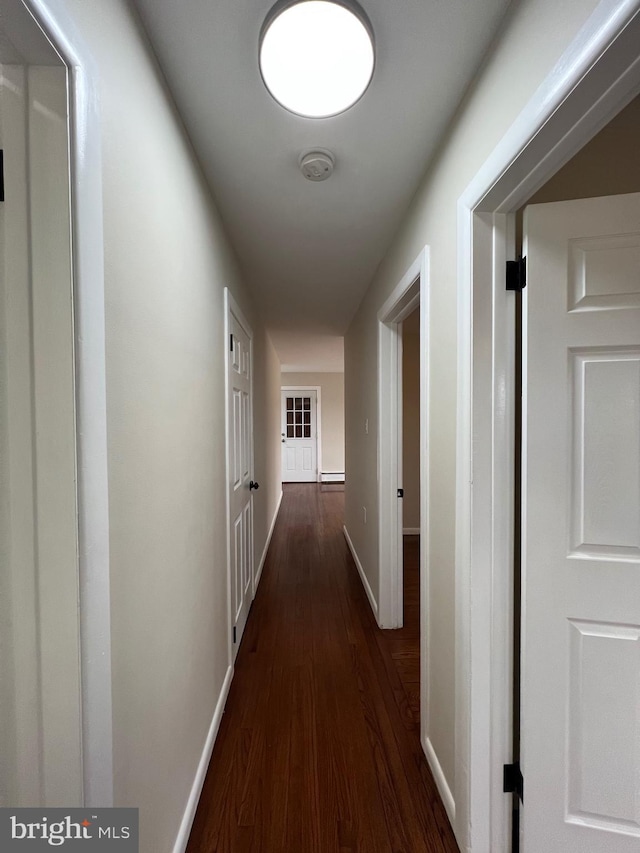 corridor with baseboard heating and dark hardwood / wood-style floors