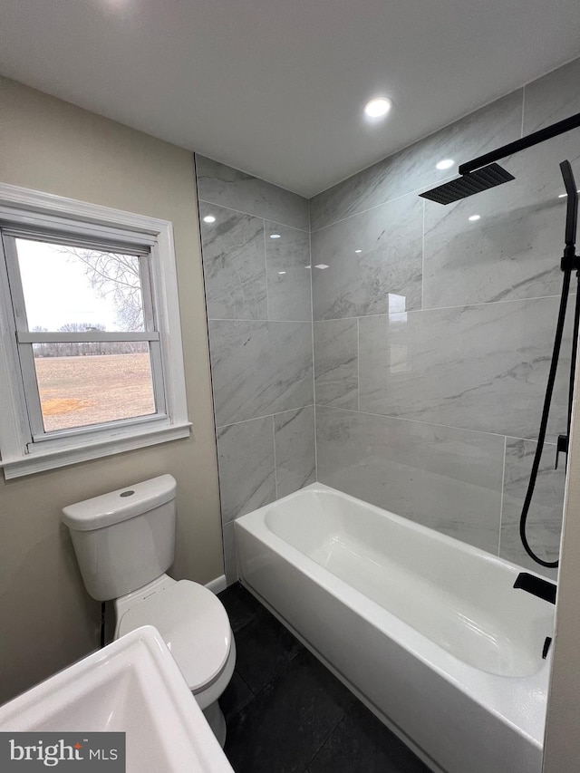 bathroom with toilet, tiled shower / bath combo, and tile patterned flooring