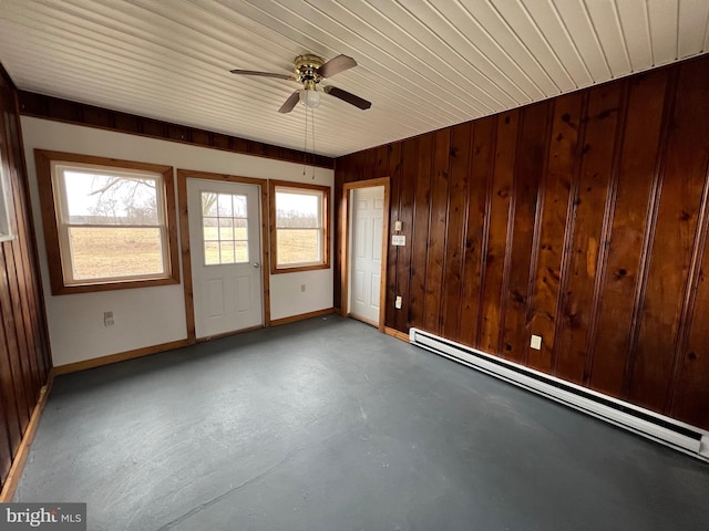 spare room with wood ceiling, wood walls, ceiling fan, a baseboard radiator, and concrete flooring