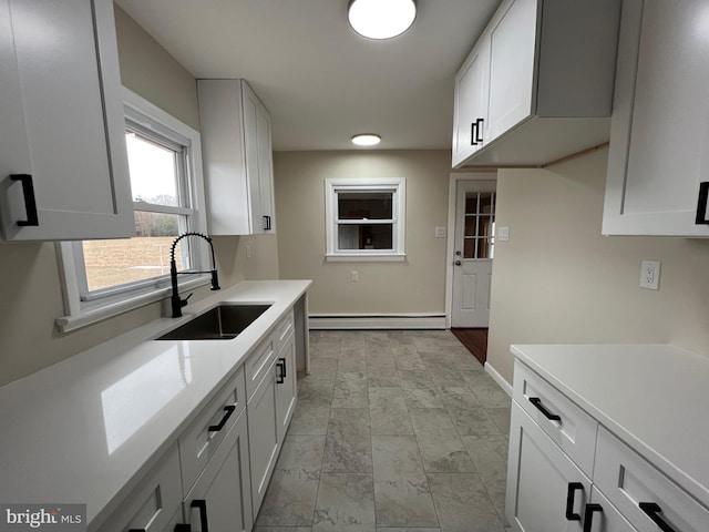 kitchen with baseboard heating, white cabinetry, and sink