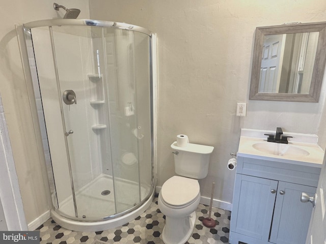 bathroom featuring tile patterned floors, vanity, toilet, and a shower with door