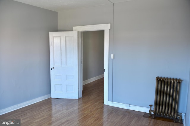 spare room with radiator heating unit and dark wood-type flooring