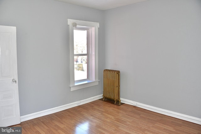 spare room featuring hardwood / wood-style floors, radiator heating unit, and a wealth of natural light