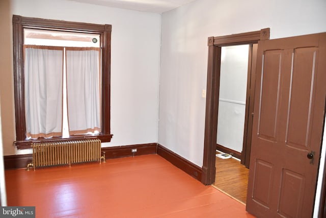 unfurnished room featuring wood-type flooring and radiator