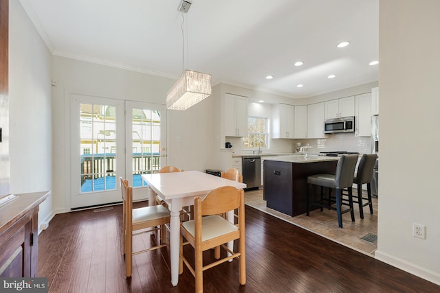 dining space featuring a chandelier, crown molding, sink, and dark wood-type flooring