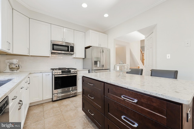 kitchen featuring tasteful backsplash, light stone counters, a breakfast bar, stainless steel appliances, and white cabinets