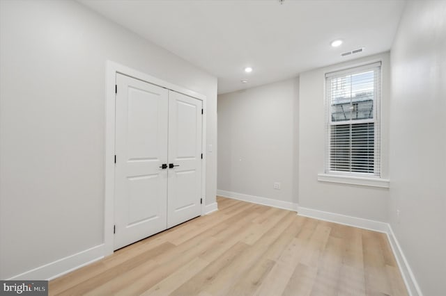 unfurnished bedroom with light hardwood / wood-style flooring and a closet