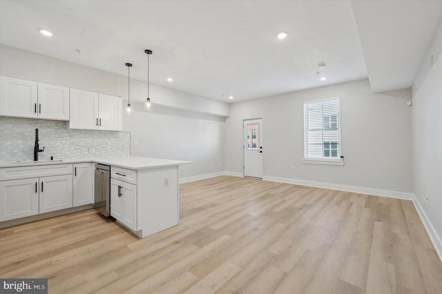 kitchen featuring kitchen peninsula, white cabinetry, hanging light fixtures, and sink