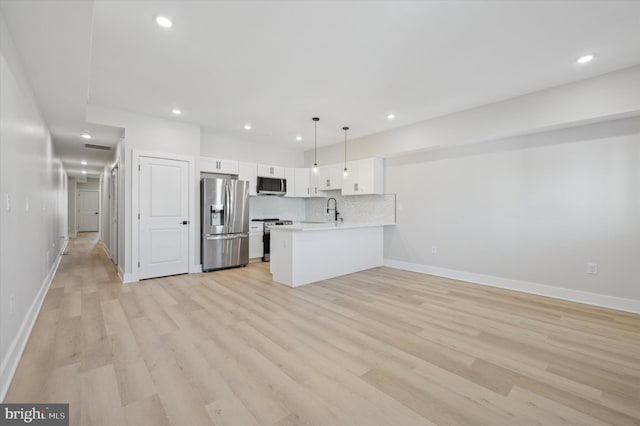 kitchen featuring pendant lighting, white cabinets, sink, appliances with stainless steel finishes, and kitchen peninsula