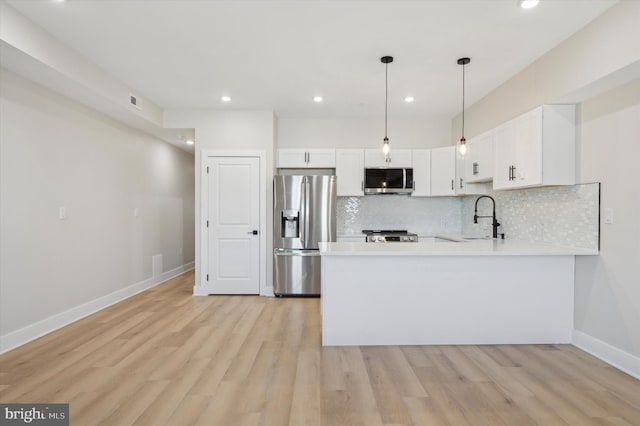 kitchen with kitchen peninsula, sink, white cabinetry, and stainless steel appliances