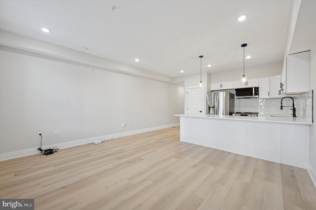 kitchen with tasteful backsplash, stainless steel appliances, sink, decorative light fixtures, and white cabinets