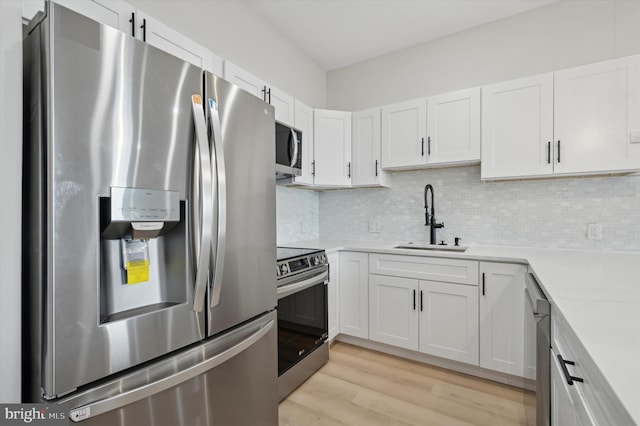 kitchen featuring appliances with stainless steel finishes, backsplash, white cabinetry, and sink