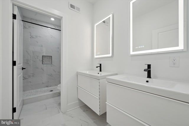 bathroom with a tile shower and vanity