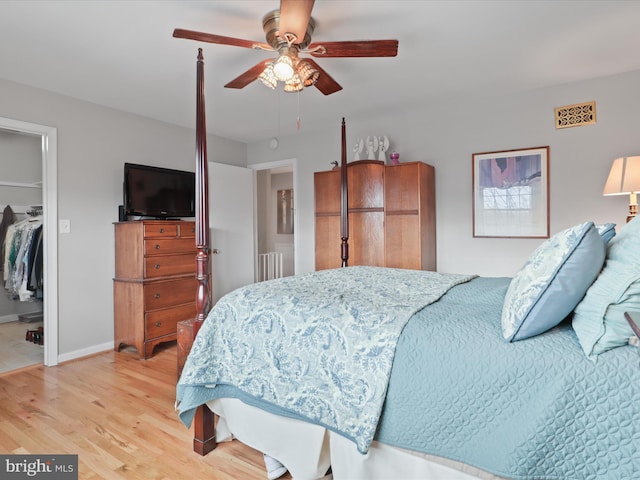 bedroom with ceiling fan, a closet, a spacious closet, and light hardwood / wood-style flooring