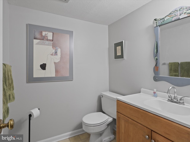 bathroom with vanity, toilet, and a textured ceiling