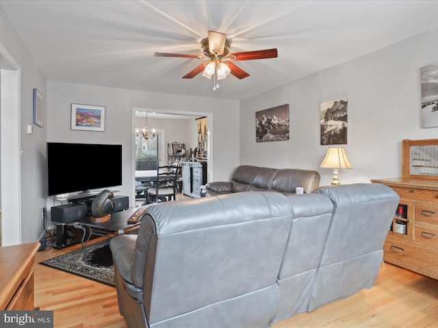 living room with ceiling fan with notable chandelier and light hardwood / wood-style flooring