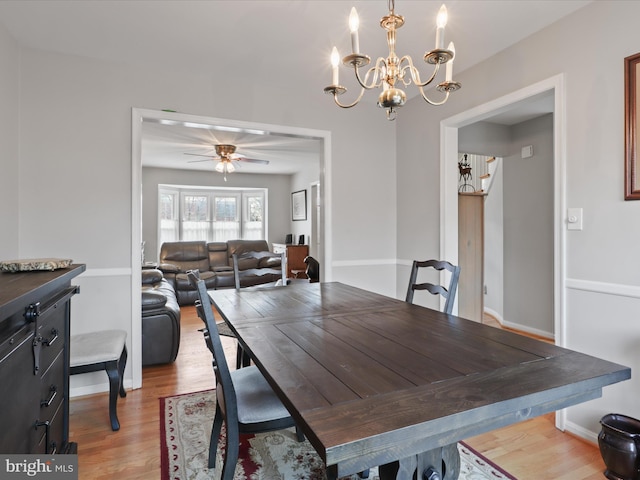 dining space with ceiling fan with notable chandelier and wood-type flooring