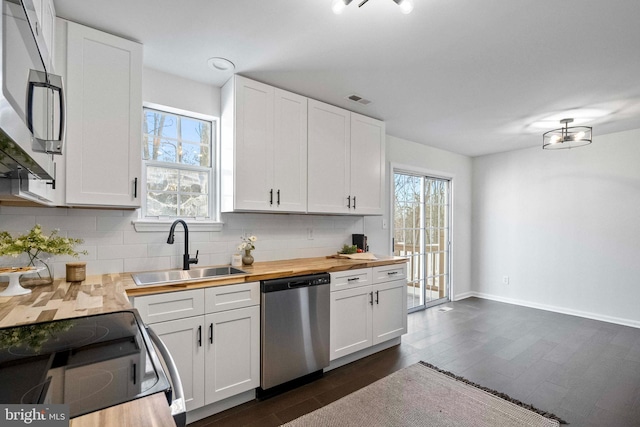 kitchen with white cabinets, sink, butcher block counters, and stainless steel appliances