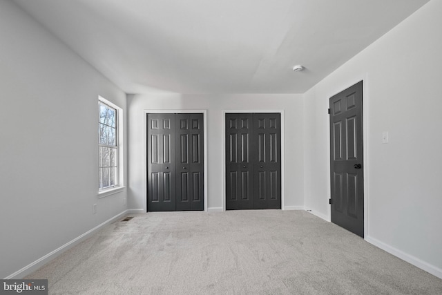 unfurnished bedroom with light carpet and two closets