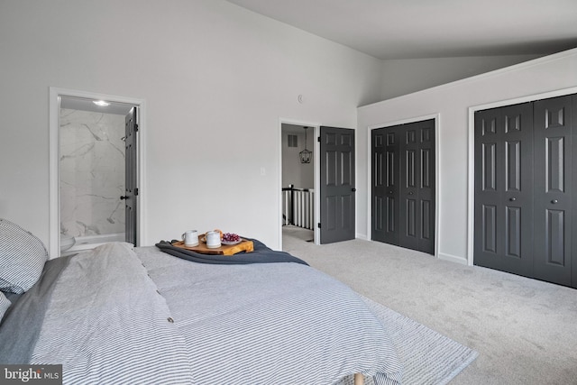 bedroom featuring carpet flooring, ensuite bath, high vaulted ceiling, and two closets