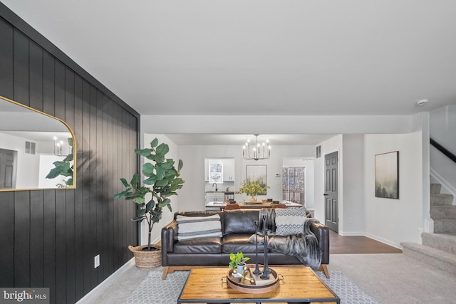 carpeted living room featuring a notable chandelier and wooden walls