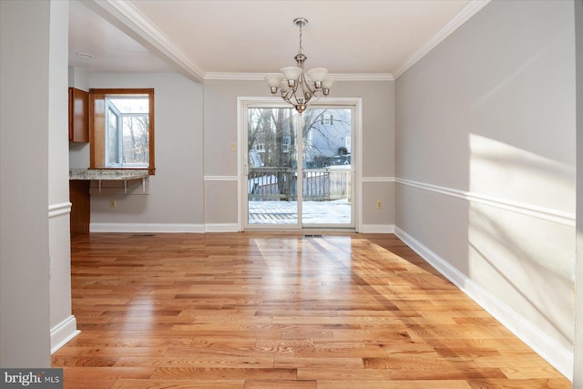 unfurnished dining area featuring crown molding, a chandelier, light hardwood / wood-style flooring, and a healthy amount of sunlight