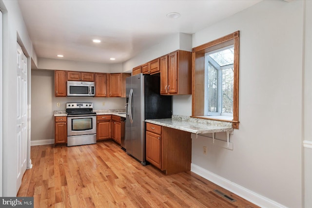 kitchen featuring light stone countertops, light wood-type flooring, and appliances with stainless steel finishes