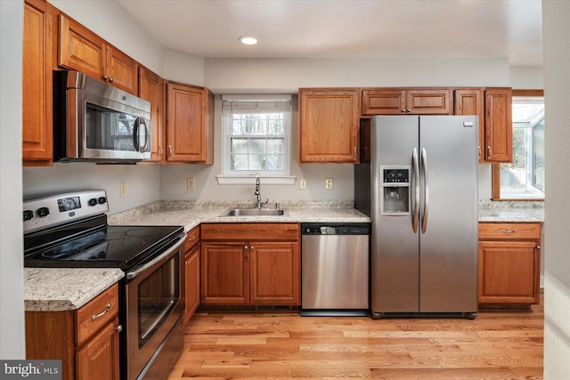 kitchen featuring stainless steel appliances, light hardwood / wood-style floors, a wealth of natural light, and sink