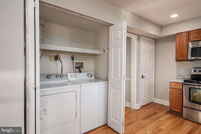 laundry area with light hardwood / wood-style floors and washing machine and clothes dryer