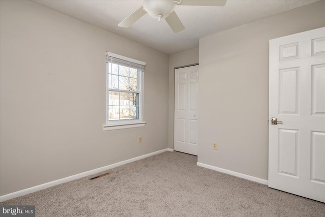 unfurnished bedroom with a closet, light carpet, and ceiling fan