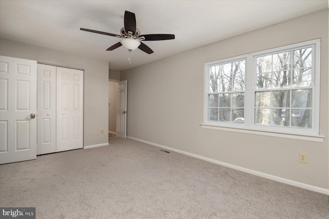 unfurnished bedroom featuring ceiling fan, light colored carpet, and a closet