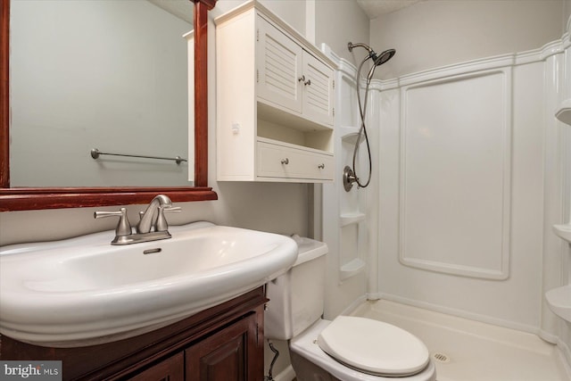 bathroom featuring sink, walk in shower, and toilet