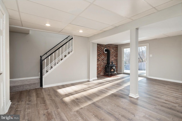 interior space featuring wood-type flooring, a wood stove, and a paneled ceiling