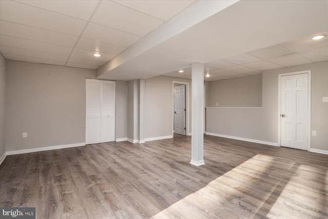 basement with hardwood / wood-style flooring and a paneled ceiling