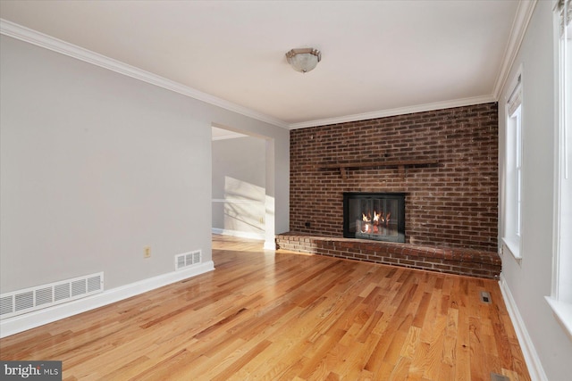 unfurnished living room with a brick fireplace, ornamental molding, and light hardwood / wood-style flooring