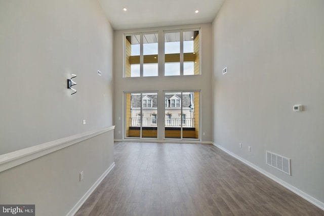 unfurnished living room with hardwood / wood-style floors and a towering ceiling