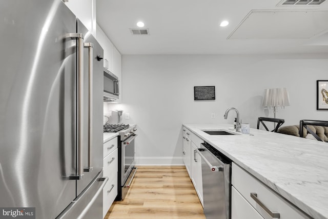 kitchen with light hardwood / wood-style flooring, stainless steel appliances, white cabinetry, and sink