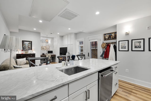 kitchen featuring white cabinets, light stone counters, sink, dishwasher, and light hardwood / wood-style floors