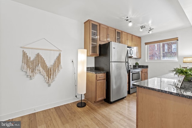 kitchen with light hardwood / wood-style floors, dark stone countertops, and stainless steel appliances