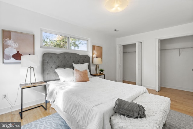 bedroom with light hardwood / wood-style flooring and two closets