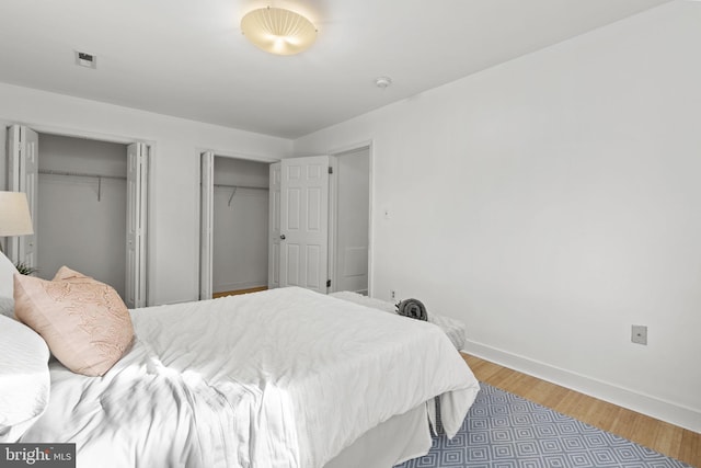 bedroom with light hardwood / wood-style floors and multiple closets