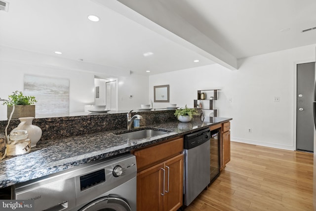 kitchen featuring sink, beam ceiling, dark stone countertops, dishwasher, and washer / dryer