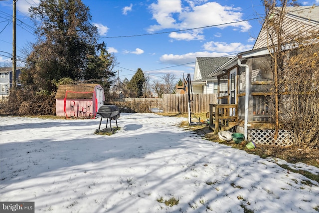 snowy yard featuring a storage shed