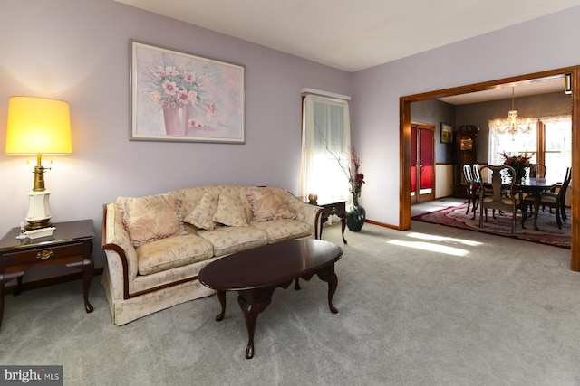 carpeted living room featuring a chandelier