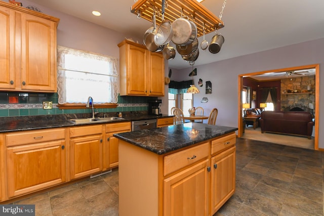 kitchen with sink, a center island, backsplash, dark stone countertops, and a fireplace