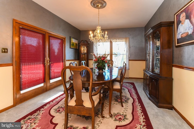 carpeted dining area with french doors and an inviting chandelier